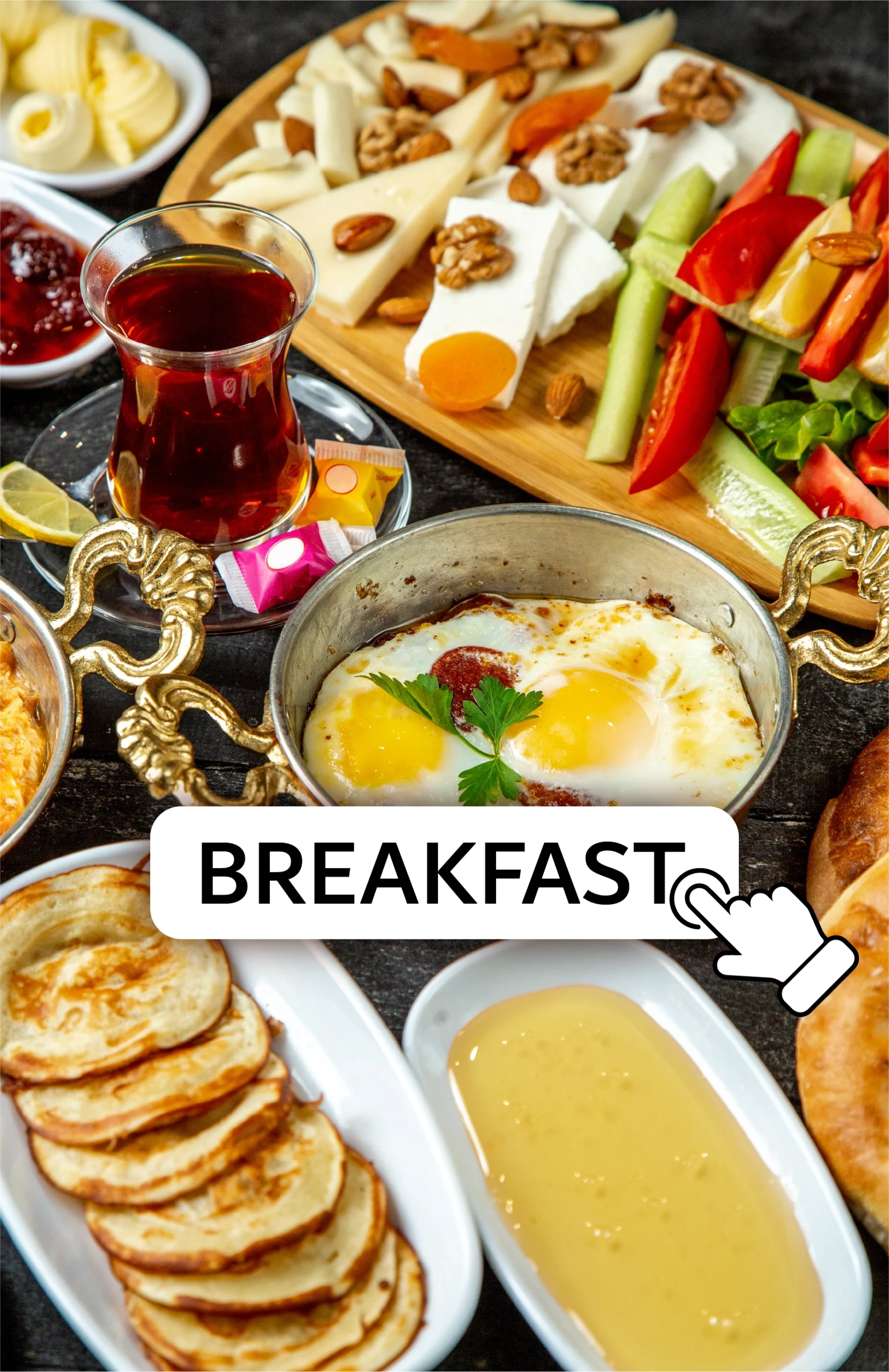 A traditional breakfast spread featuring fried eggs, assorted cheeses, fresh vegetables, pancakes, butter, tea, and honey, with a "BREAKFAST" button overlay.
